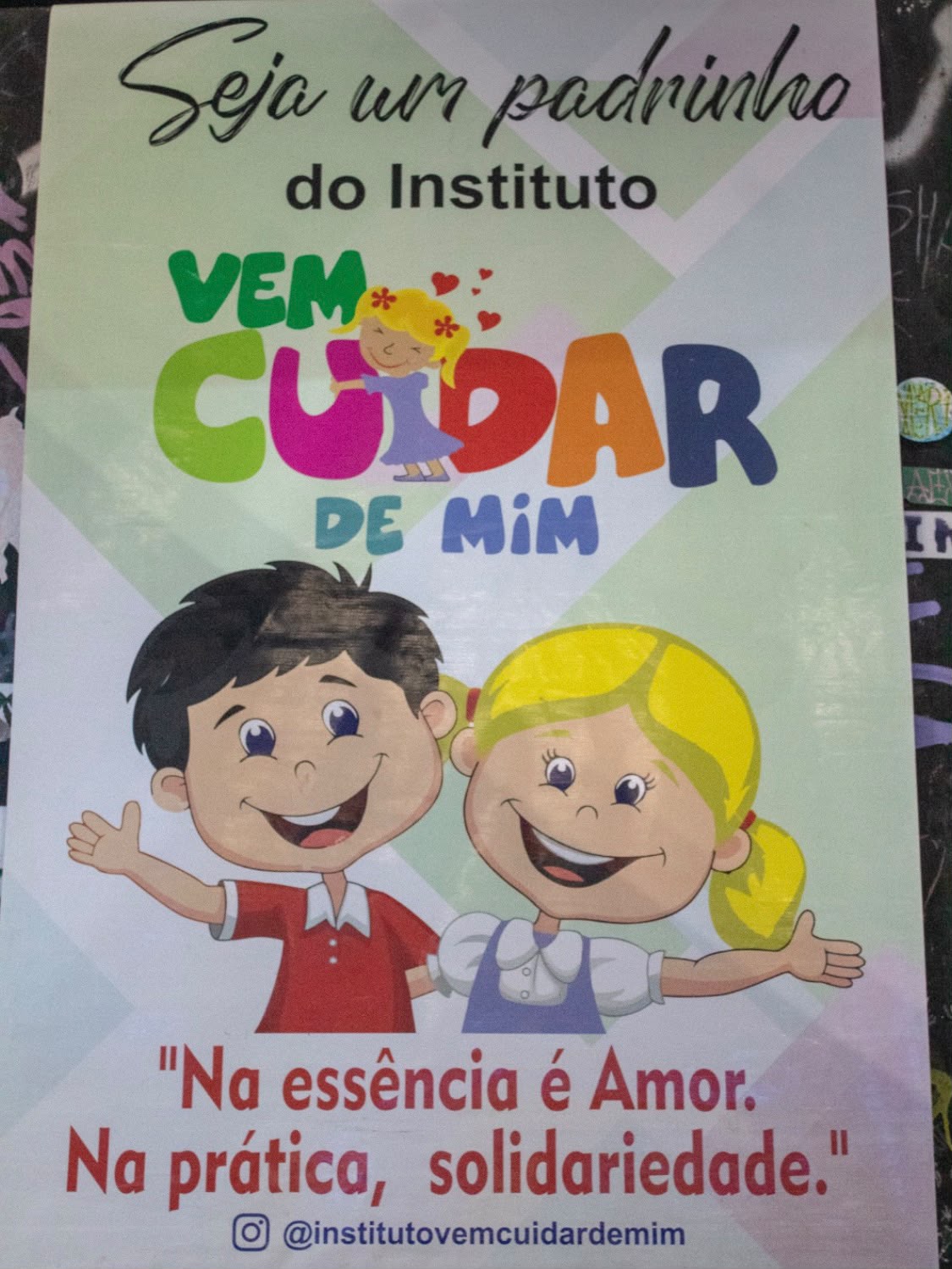 Cartaz do Instituto colado no muro, com a frase Na essência é amor, na prática solidariedade