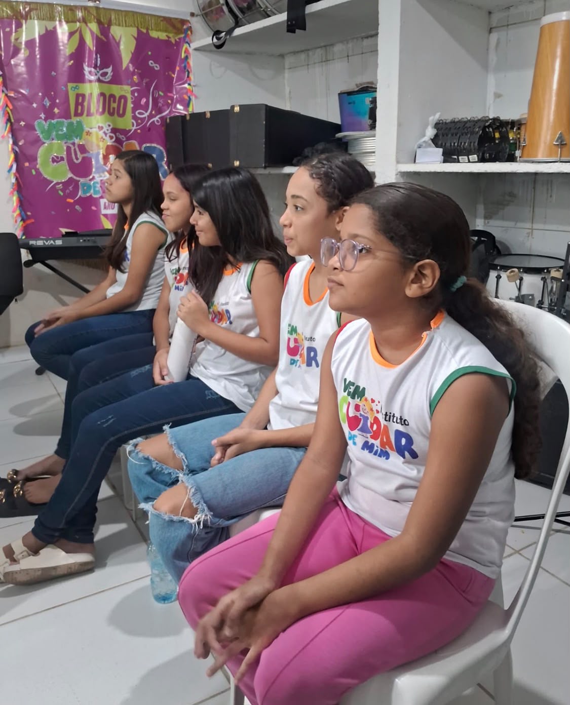 Cinco meninas do Instituto sentadas lado a lado, assistindo a uma atividade